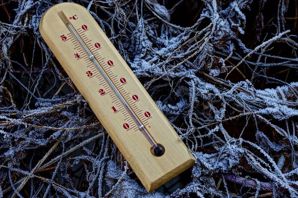 Wooden thermometer in white snow 
