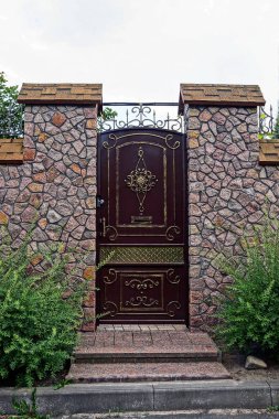 Kahverengi demir kapı üzerinde bir taş çit desenleri ile