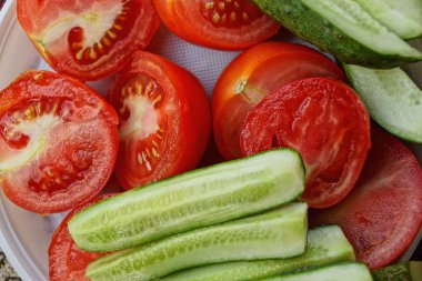 kırmızı domates ve yeşil salatalık beyaz plastik tabağa dilimlenmiş