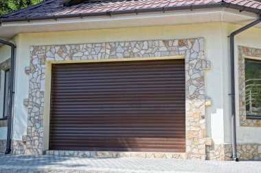 kahverengi plastik kapılar garaj gri kaldırım yakınındaki taş duvar