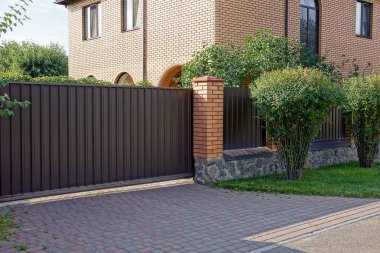 kahverengi kapalı kapılar ve yeşil bitki örtüsü ile büyümüş çit parçası