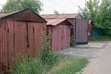 Eski kahverengi demir garajlar çim çalılıkları içinde yola yakın: