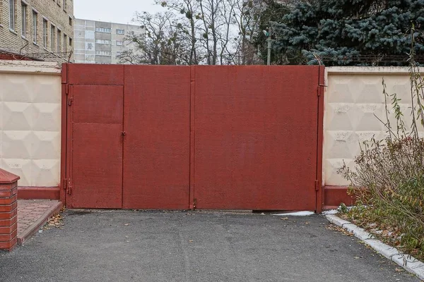 红色封闭的金属门和沥青路面围栏的一部分 — 图库照片