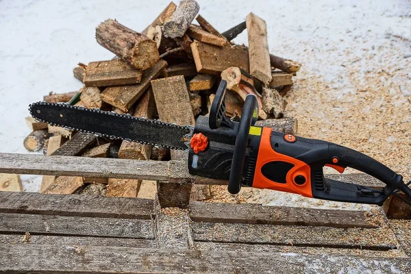 one chain saw in a pile of wooden firewood in the street