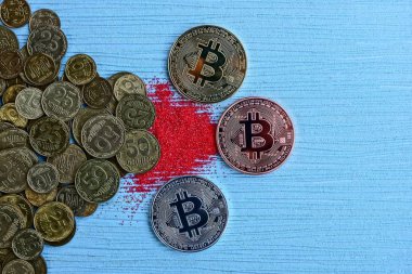 Üç sikke bitcoin bir mavi masa ve sikke yığını, kırmızı kum