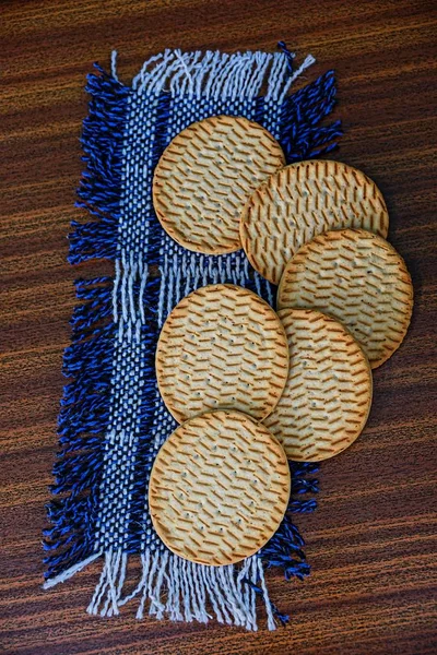 Round cookies on a woolen shawl lying on a wooden table
