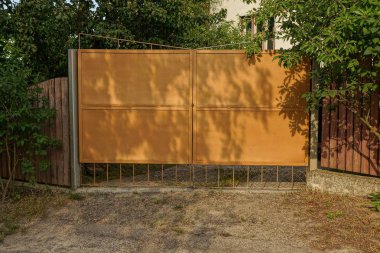 yeşil bitki örtüsü ile büyümüş Caddesi üzerinde kahverengi metal kapılar