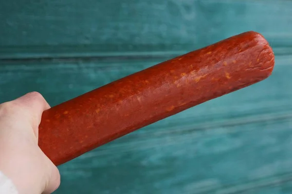 Red Long Stick Salami Sausage Hand Green Background — Stock Photo, Image