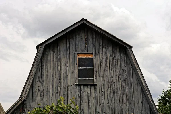 一个灰色的房子的门面与一个小窗口在天空背景 — 图库照片