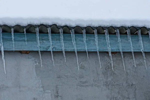 Una Fila Largos Carámbanos Techo Bajo Nieve Una Pared Hormigón — Foto de Stock