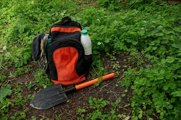 Czerwony Czarny Plecak Ubraniami Łopatą Stojącą Ziemi Zieloną Trawą — Zdjęcie stockowe