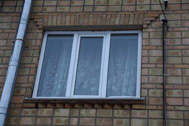 bir kahverengi tuğla duvar metal bir boru ile büyük bir beyaz kare pencere