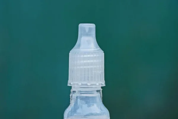 fragment of white plastic medical bottle with a cork on a green background