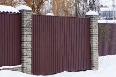 bir özel kahverengi demir çit ve kapalı bir kapı dışında beyaz karda parçası