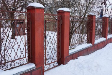 demir çubuklar ve beton beyaz kar altında bir kapı ile kırmızı bir çit parçası