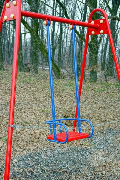 Red blue iron swing in the autumn park