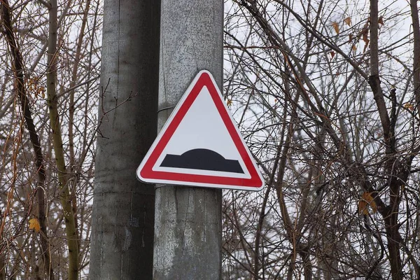 Driehoekig Road Sign Verkeersdrempel Een Betonnen Pijler Onder Boomtakken — Stockfoto