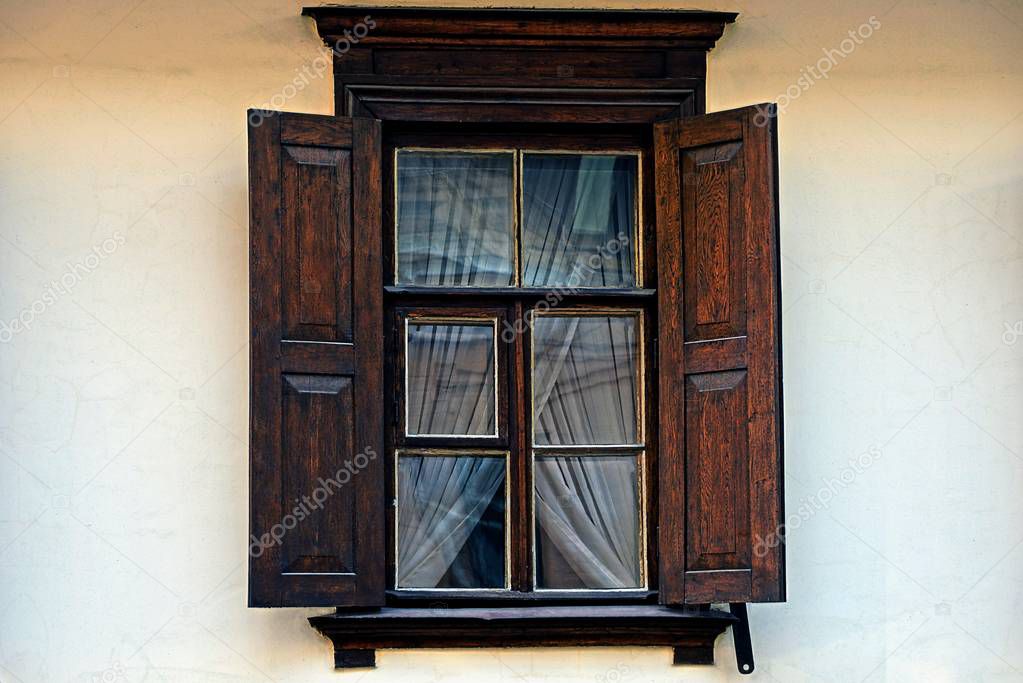 An old wooden brown window with shutters on a gray wall