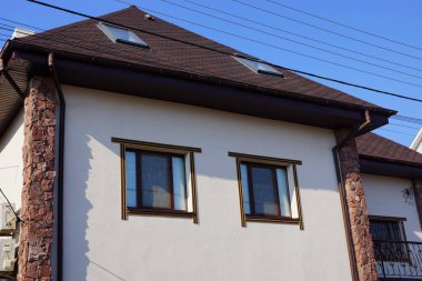 iki pencere ve kahverengi bir çatı ile gri bir ev cephe