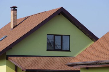 yeşil çatı katında bir pencere ve kahverengi kiremit mavi gökyüzü karşı çatıda bir ev