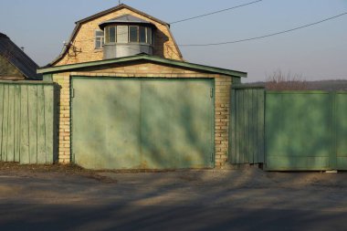 Yeşil kapı ve çit asfalt yolun yakınında sokakta parçası ile tuğla garaj