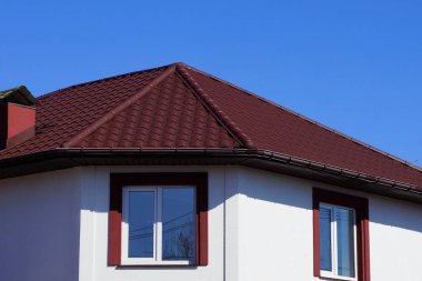 bir pencere karşı sokakta mavi gökyüzü ile büyük bir özel ev tavan çatısında kırmızı kiremit