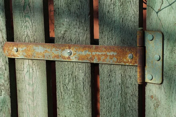 绿色木制栅栏板上生锈的铰链 — 图库照片