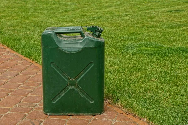 The green canister on the sidewalk near the lawn