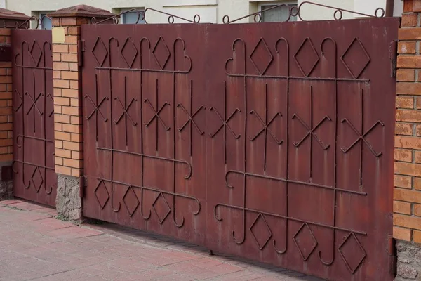 棕色金属门与锻造图案和砖栅栏在街道上 — 图库照片
