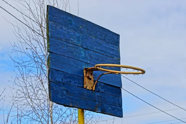 空と枝に対して黄色いリングにブルーの古い木製のバスケット ボール バックボード — ストック写真