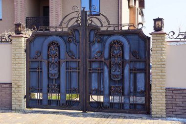 bir büyük kahverengi gri metal geçit dövme deseni ve sokağın ortasında bir tuğla çit parçası ile