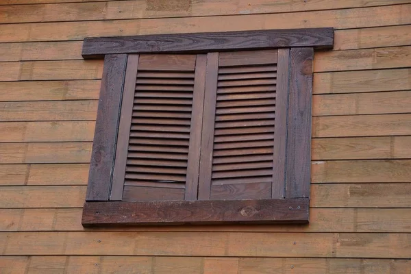 window covered with brown wooden shutters on the wall of boards