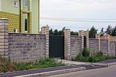 sokakta kapalı yeşil kapı ve gri tuğla çit