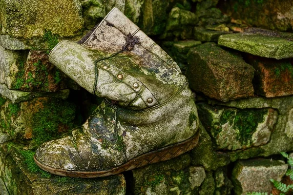 老灰色靴子长满青苔在泥上的岩石 — 图库照片