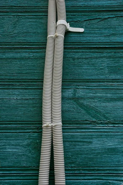 Cable in gray insulation on a wooden green wall