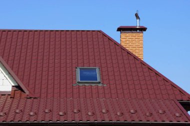 Gökyüzüne karşı bir pencere ve bir tuğla boru ile çatıda kırmızı fayans ile evin bir parçası
