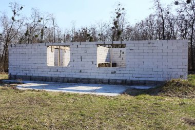 sokakta yeşil çim tamamlanmamış gri tuğla ev ile inşaat sitesi