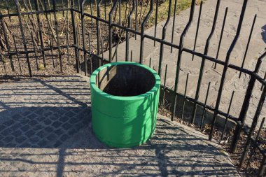 yeşil bir beton urn demir siyah çit yakın gri bir kaldırım üzerinde duruyor