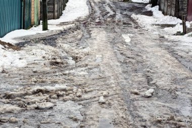 Su birikintileri ve kar çukurları ile kirli yol