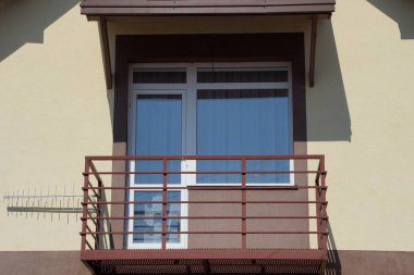 evin duvarında pencere ve kapı ile açık kahverengi balkon