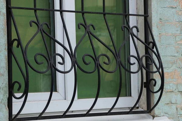 black iron grill with forged pattern on a glass window