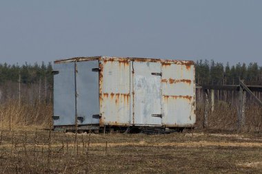 gri metal eski konteyner gökyüzüne karşı kuru çim duruyor