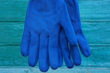 yeşil bir duvara asılı iki mavi iş eldiveni