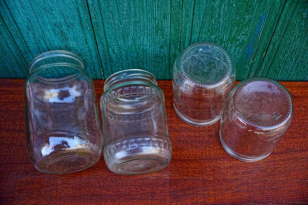 Uma Linha Frascos Vidro Uma Mesa Vermelha Perto Uma Parede — Fotografia de Stock