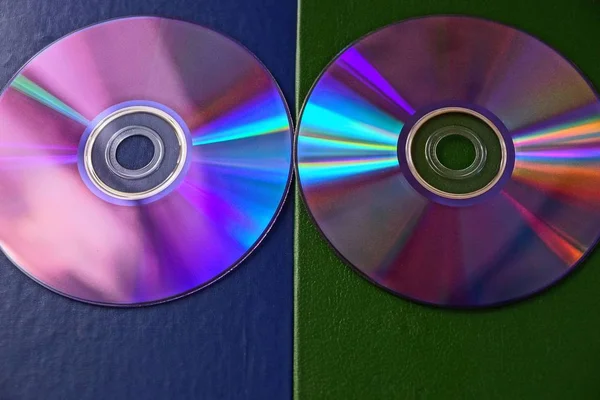 Two compact discs on a blue green surface