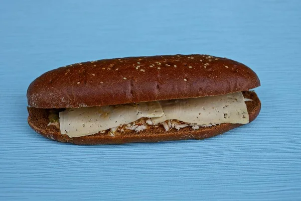 Brown sandwich with cheese on a blue table