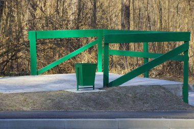 yeşil bir vazo yol tarafından asfalt üzerinde kalasyapılmış ahşap bir çit tarafından duruyor