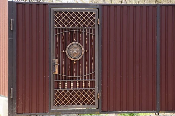 private brown gate and metal fence with forged pattern on the street