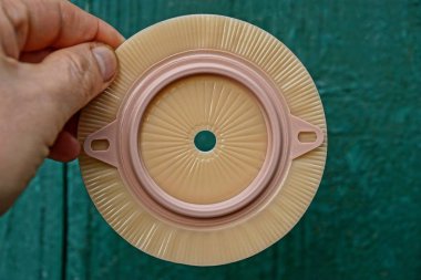 parmaklar kahverengi plastik kolostomi torbası yeşil bir duvar tutun