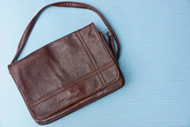 mavi bir masa üzerinde kahverengi deri çanta